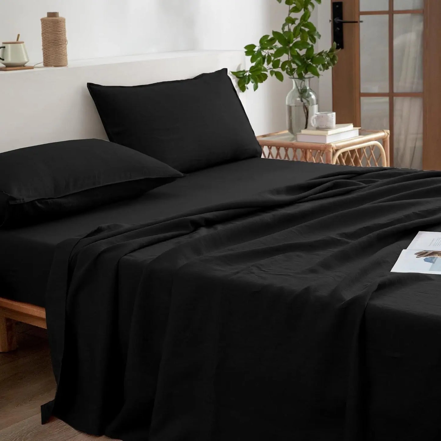 Black bed sheets and pillows on a bed in a bedroom setting.