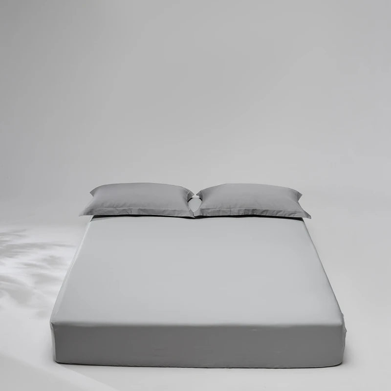 Gray mattress cover with two pillows on a plain background