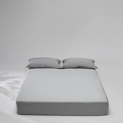 Gray mattress cover with two pillows on a plain background