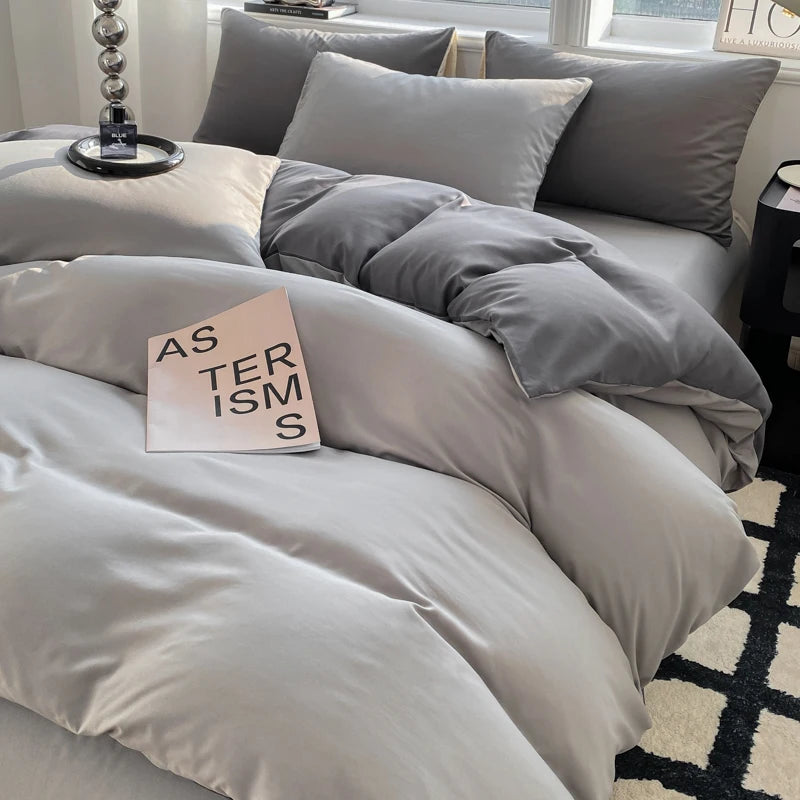 Gray bedding set on a bed with a book titled 'Asterisms' on top.