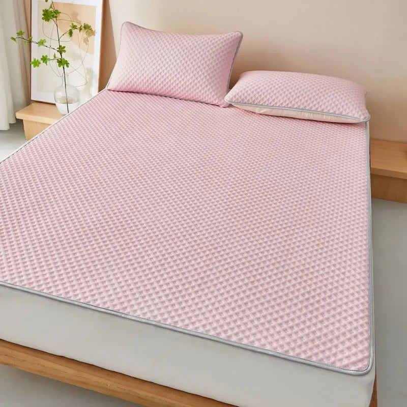 Pink quilted mattress cover with two pillows on a bed in a bedroom setting.