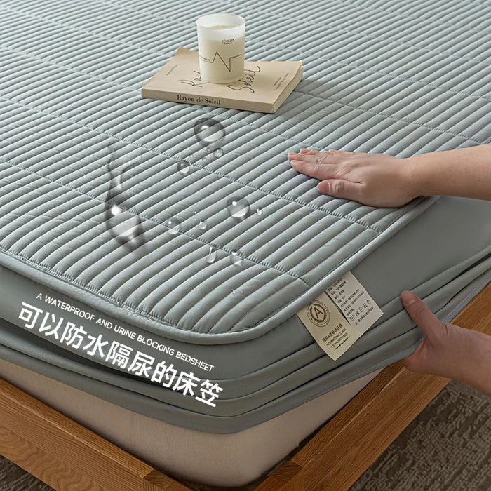 Gray waterproof bedsheet with a hand touching it, showing its texture and design.
