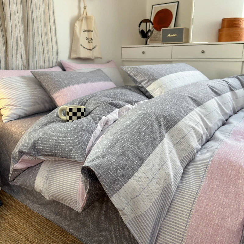 Bed with gray and pink checkered comforter in a bedroom setting