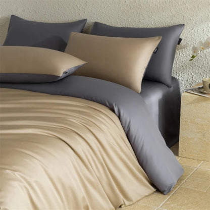 Beige and gray bedding set on a bed with pillows against a neutral wall.