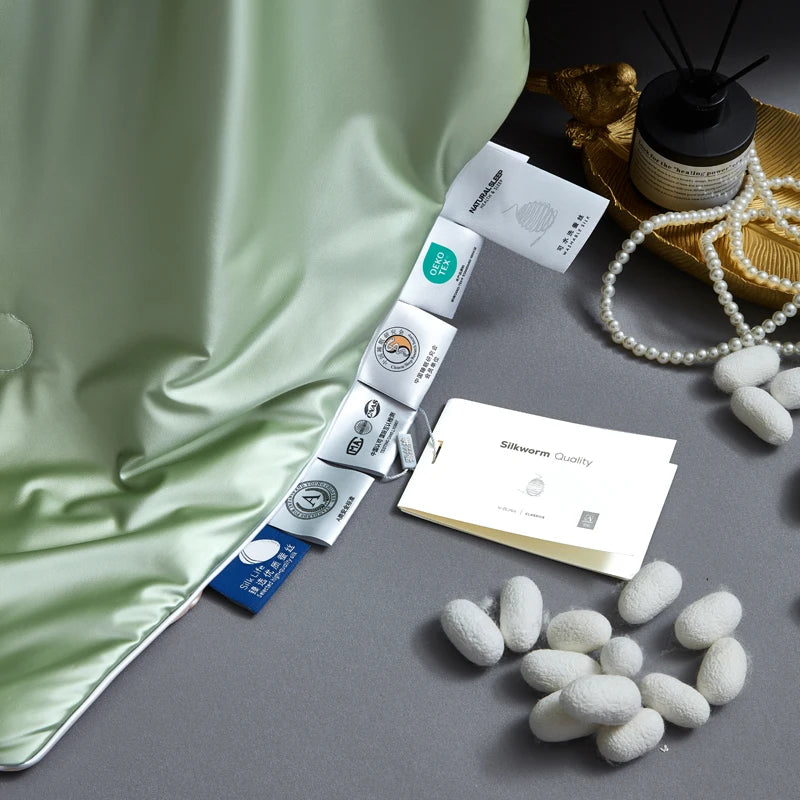 Silkworm cocoons and silk products on a gray surface with green fabric.