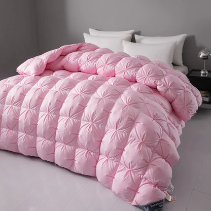 Pink quilted comforter on a bed with white pillows against a gray wall.