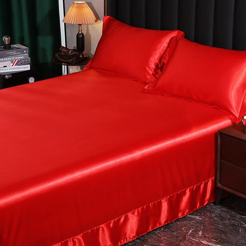 Red satin bedspread on a bed with matching pillows in a bedroom setting.