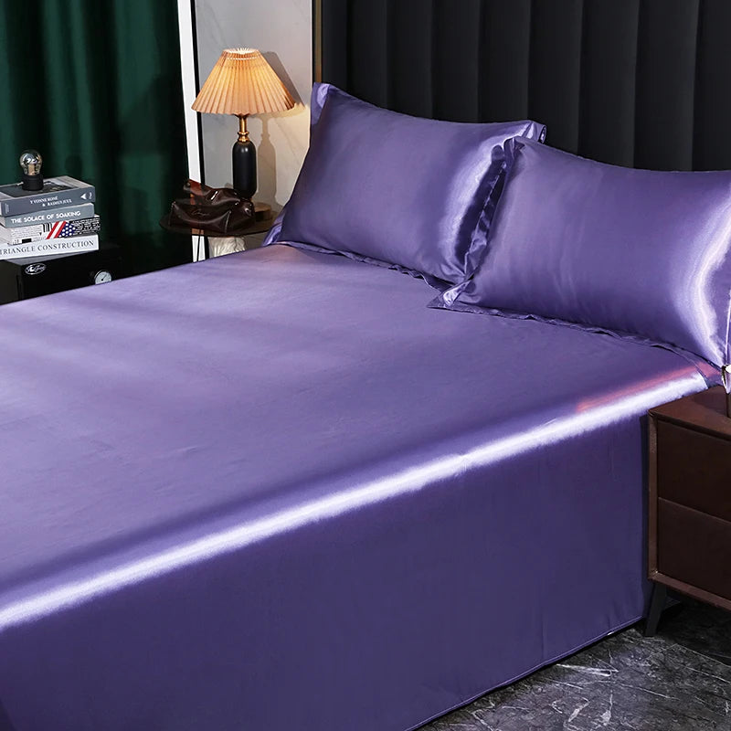 Purple satin bedding set on a bed with a lamp and books in the background.