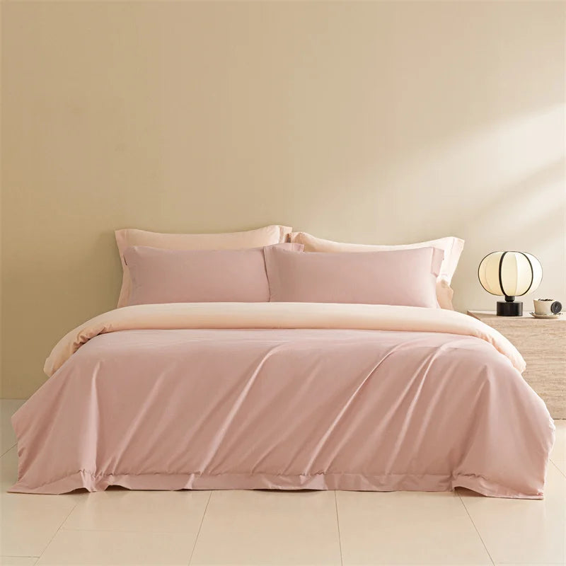 Pink bedding set on a bed in a room with a beige wall and lamp.