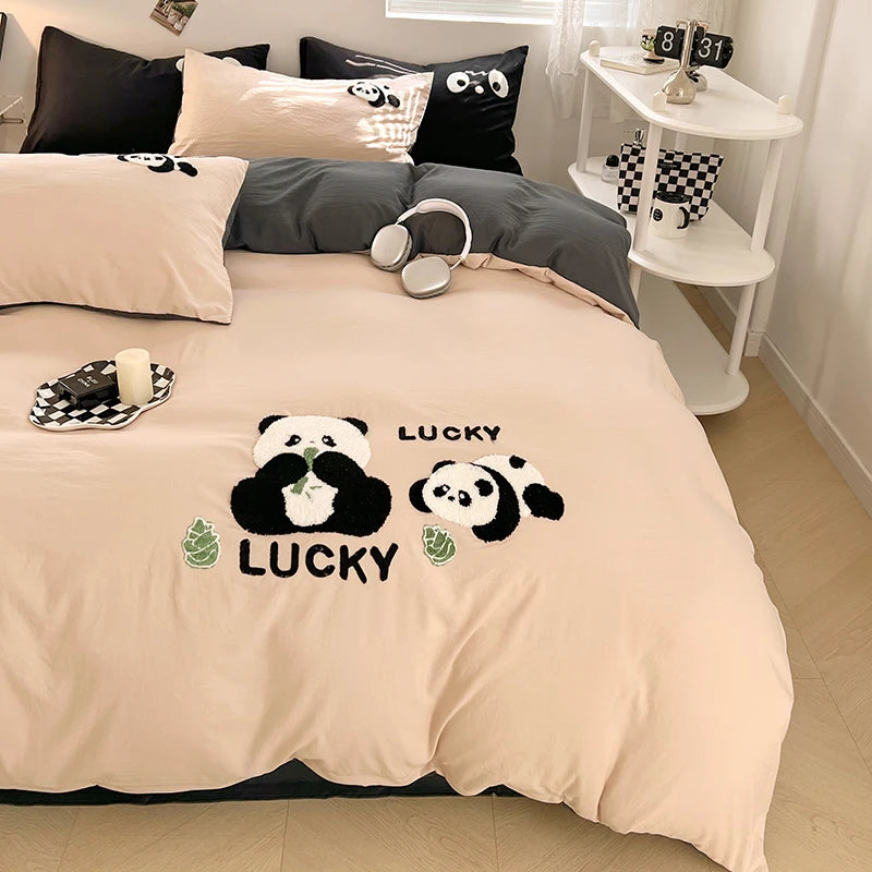 Beige bedspread with panda design and 'Lucky' text on a bed in a room.