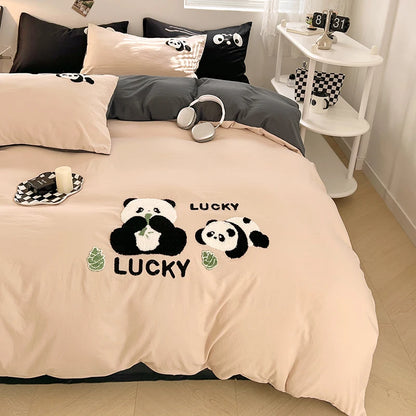 Beige bedspread with panda design and 'Lucky' text on a bed in a room.