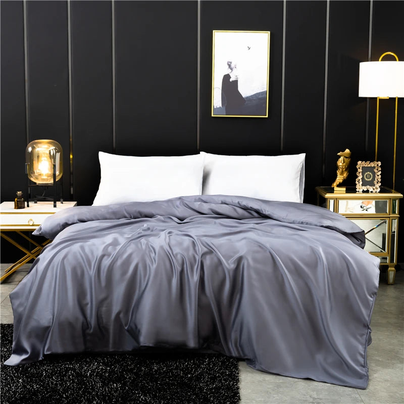 Gray comforter on a bed in a stylish bedroom with dark walls and decorative items.