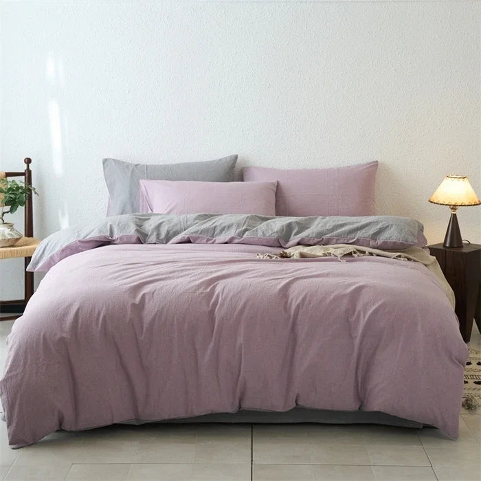 Bed with purple bedding and pillows in a room setting