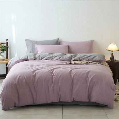 Bed with purple bedding and pillows in a room setting