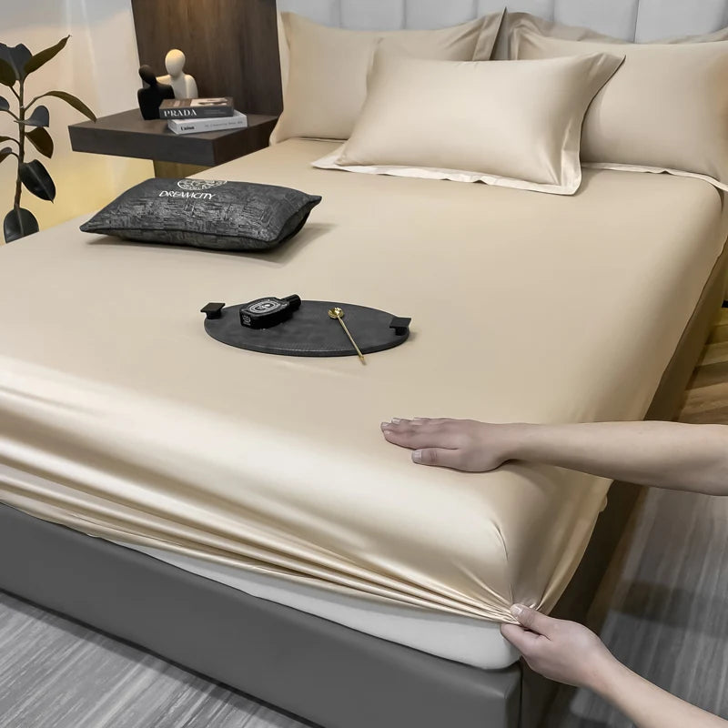 Beige satin sheet being fitted onto a bed with a person's hand assisting.