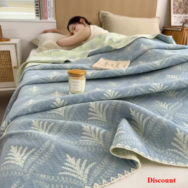 Person sleeping under a blue patterned blanket with a candle on a nightstand.