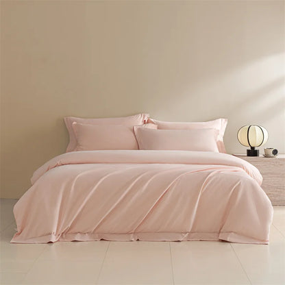Pink bedding set on a bed in a minimalistic bedroom with a beige wall and light-colored floor.