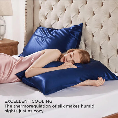 Woman lying on a bed with blue satin pillows, emphasizing comfort and cooling properties.