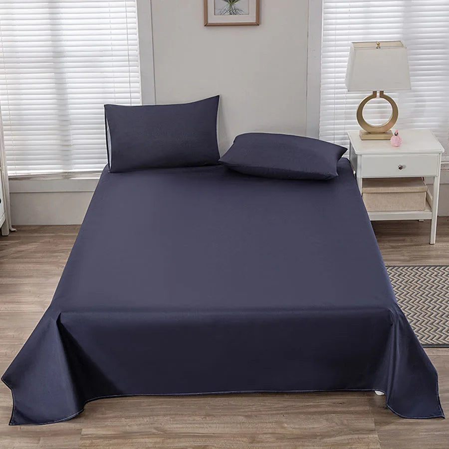 Navy blue bedspread set on a bed in a bedroom with a lamp and nightstand.