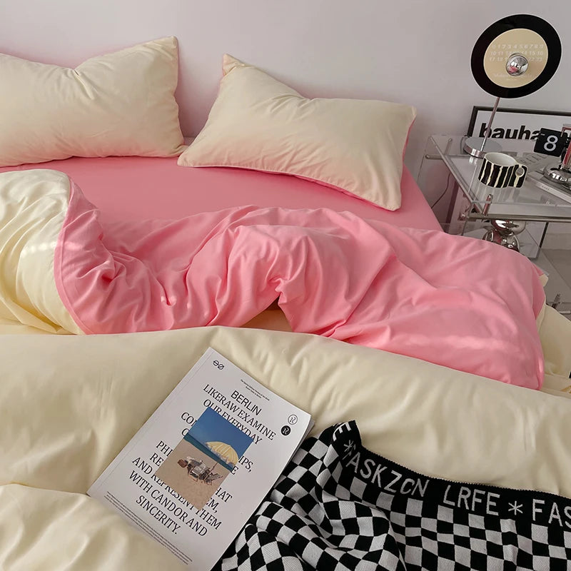 Pink and yellow bedding with a book and checkered pants on a bed.