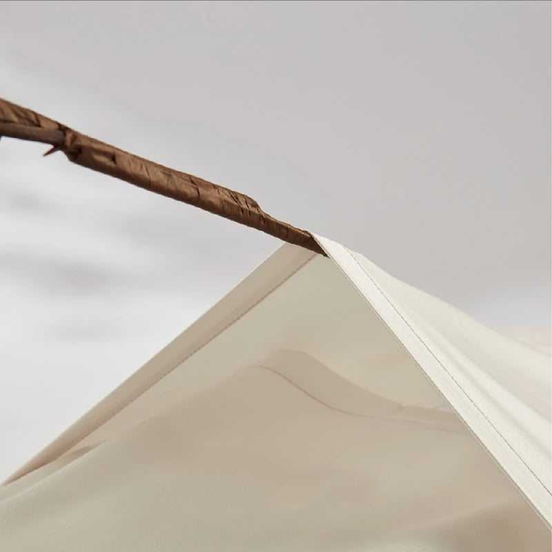 Close-up of a beige tent with a wooden pole against a light gray background