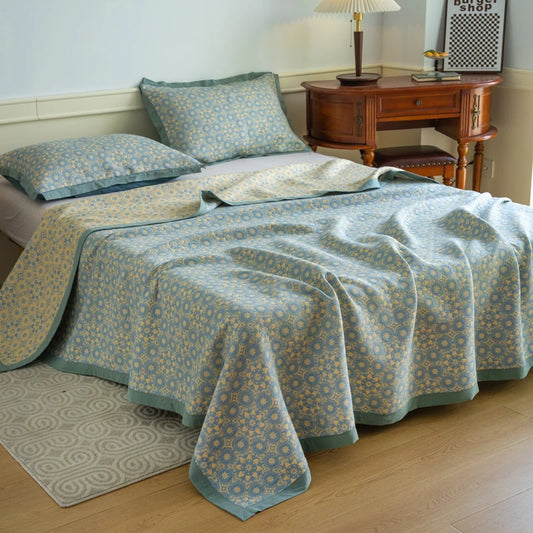 Bed with a patterned blue and green comforter in a bedroom setting.
