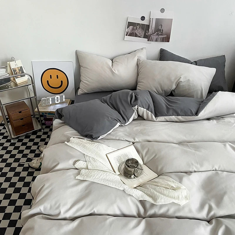 Neatly made bed with gray and white bedding in a room with a checkered floor.
