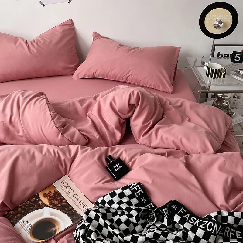 Pink bedding set on a bed with a coffee table and decorative items in the background.