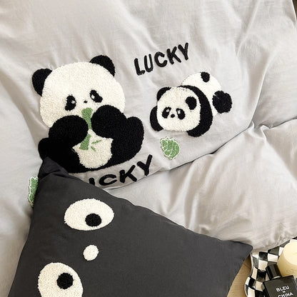 Pillows with panda designs and 'LUCKY' text on a bed.