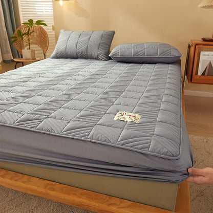 Gray quilted mattress cover on a bed in a bedroom setting