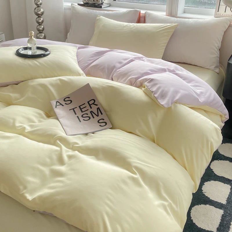 Yellow bedding set on a bed with a book titled 'Asterisms' in a bedroom setting.