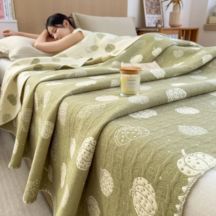 Woman sleeping under a green patterned blanket with a candle on a nightstand.