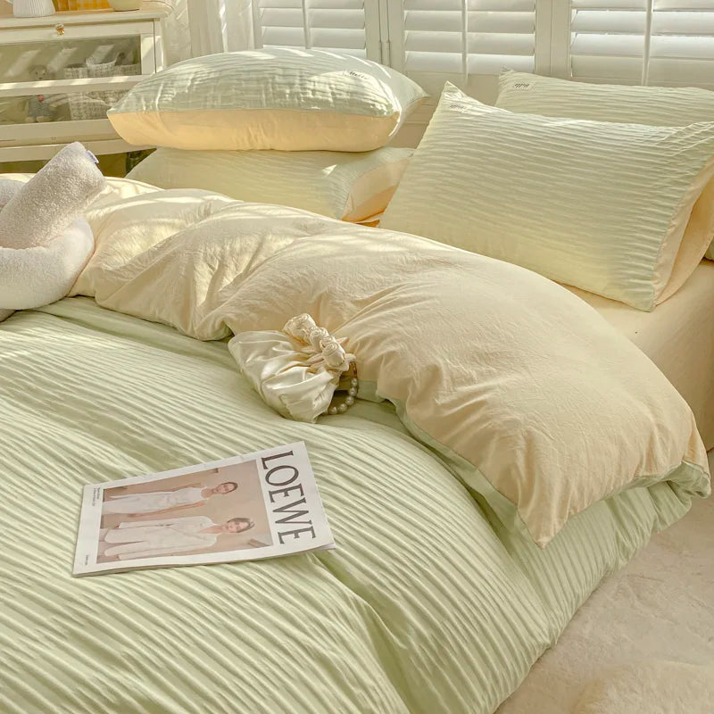 Neatly made bed with light-colored bedding and pillows, featuring a Loewe magazine.