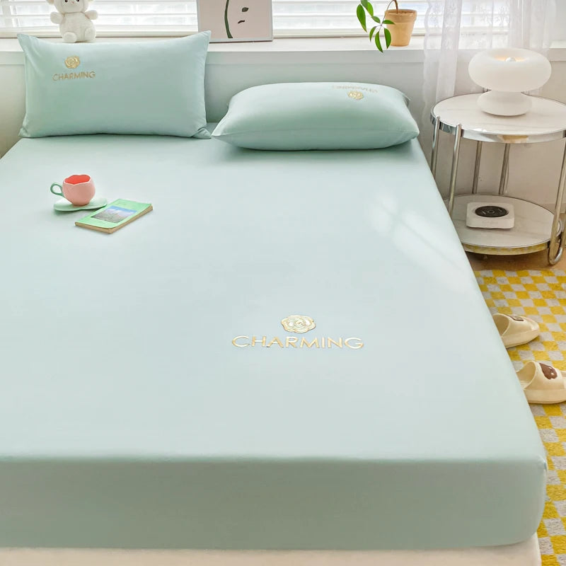 Light green mattress cover with 'Charming' branding on a bed in a bedroom setting.
