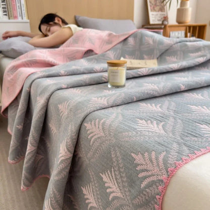 Person sleeping under a pink and gray patterned blanket with a candle on a nightstand.