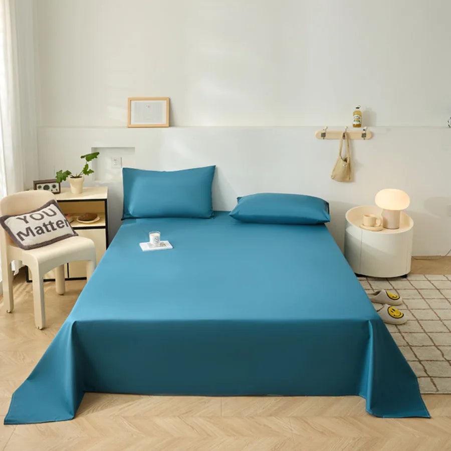 Blue bedspread on a bed in a room with a chair and lamp.