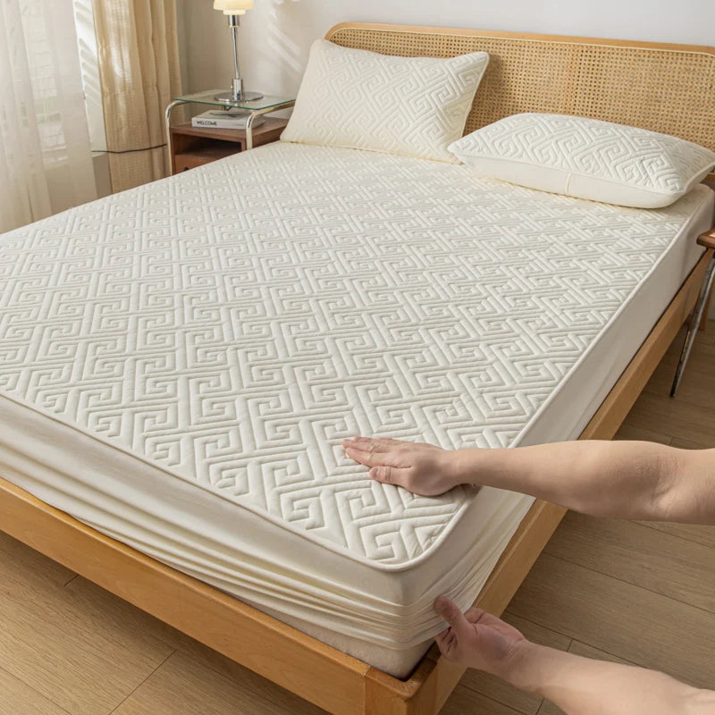 Person adjusting a mattress cover on a bed in a bedroom setting