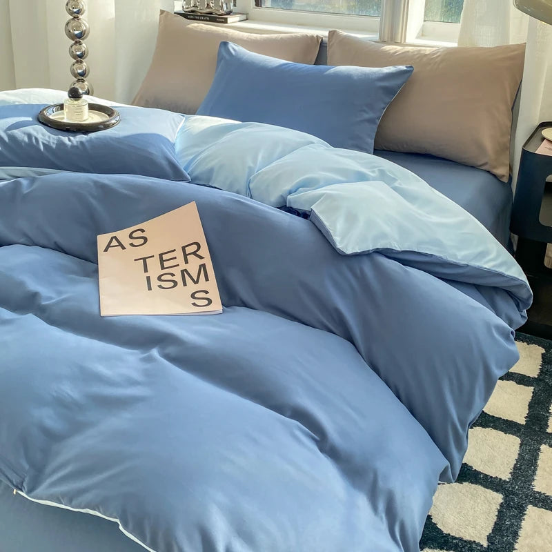 Blue bedding set on a bed with a book titled 'As Terisms' on top.