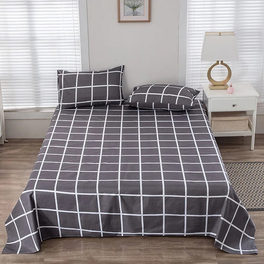 Gray checkered bedspread on a bed in a bedroom with a nightstand and lamp.