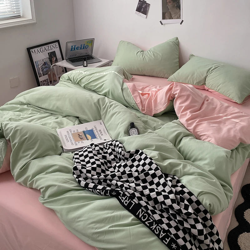 Bed with green and pink bedding, checkered pants, and a laptop on a desk.
