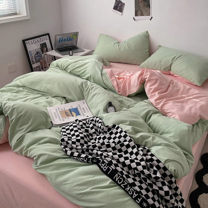 Bed with green and pink bedding, checkered pants, and a laptop on a desk.