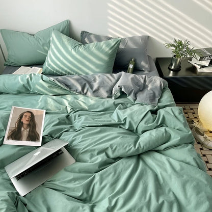 Bed with teal bedding and pillows, laptop, and photo on a nightstand.