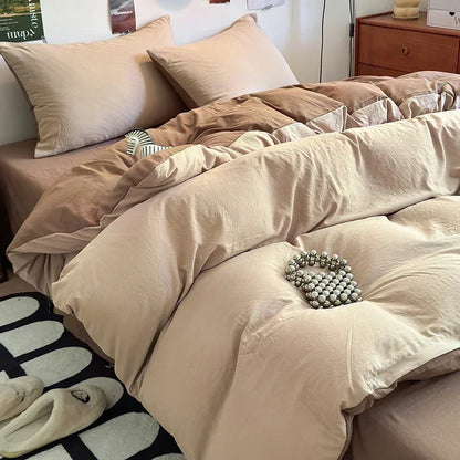 Beige comforter set on a bed with pillows and slippers in the foreground.