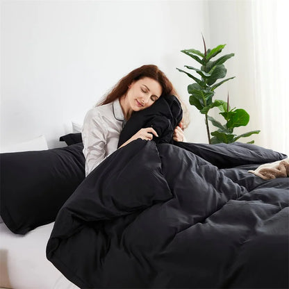 Woman wrapped in a black comforter in a cozy bedroom setting