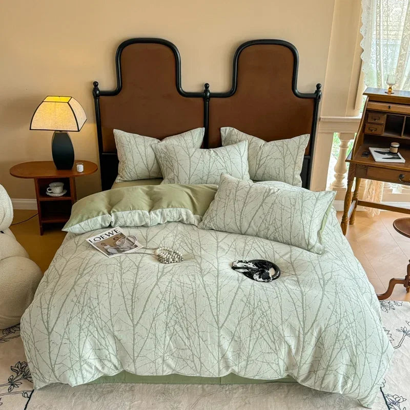 Bedroom with a bed featuring green leaf-patterned bedding, a brown headboard, and a lamp on a nightstand.