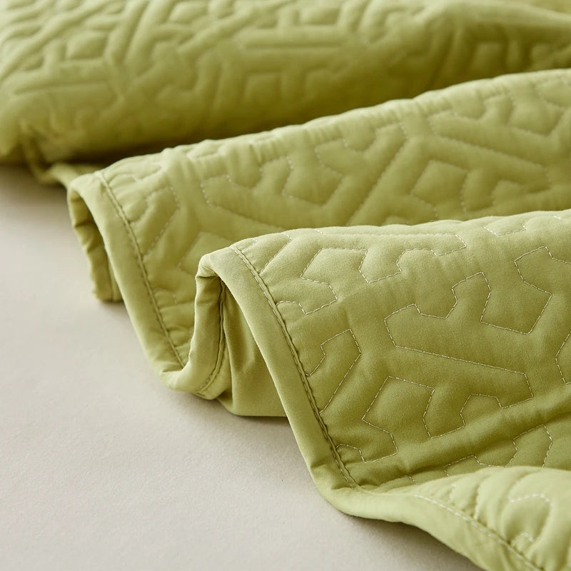 Light green quilt with textured pattern on a beige surface