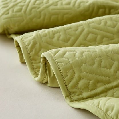 Light green quilt with textured pattern on a beige surface