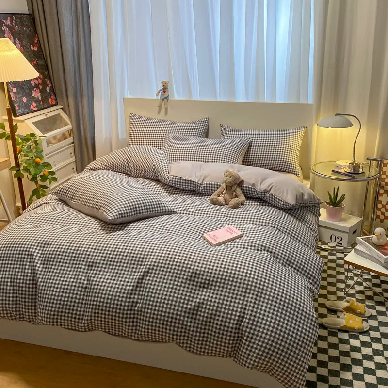 Bedroom with checkered bedding, pillows, and a teddy bear.