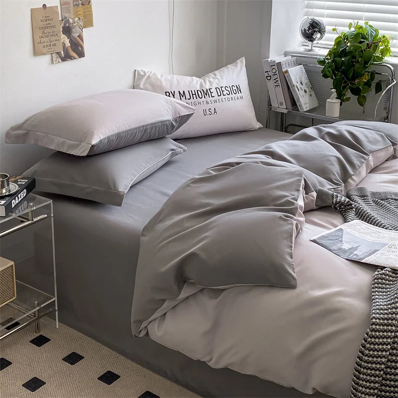 Neatly made bed with gray bedding and pillows in a bedroom setting.