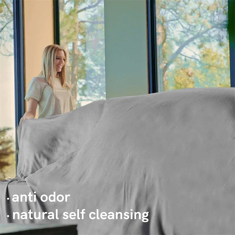Woman standing by a window with gray bedding and text 'anti odor' and 'natural self cleansing'.